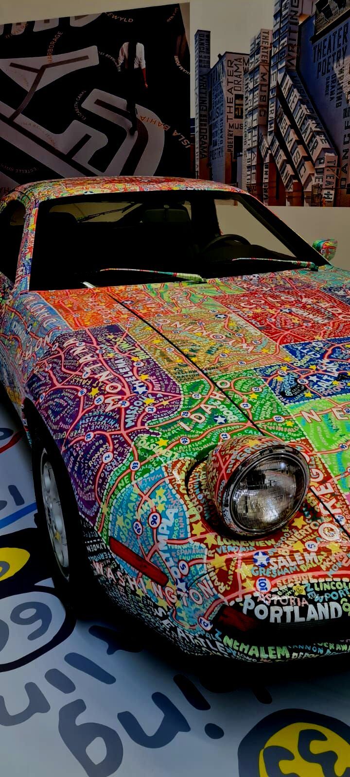 Porsche 928 wrapped in a colorful hand-drawn map livery, close-up of the front end