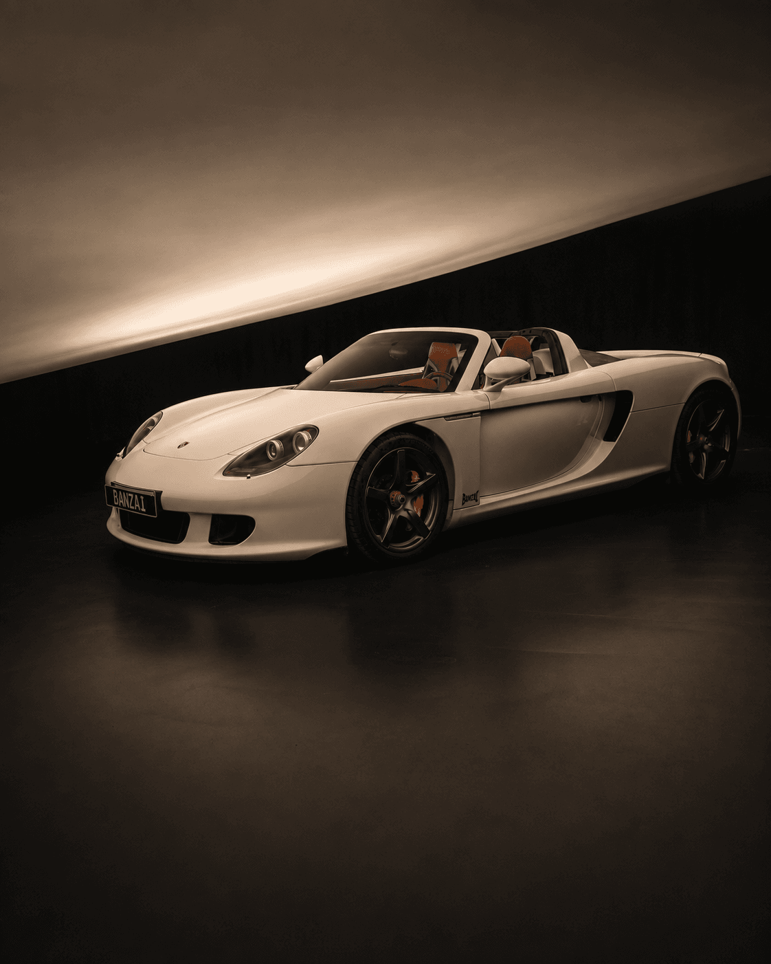 White Porsche Carrera GT studio photograph with red leather interior and BANZAI livery
