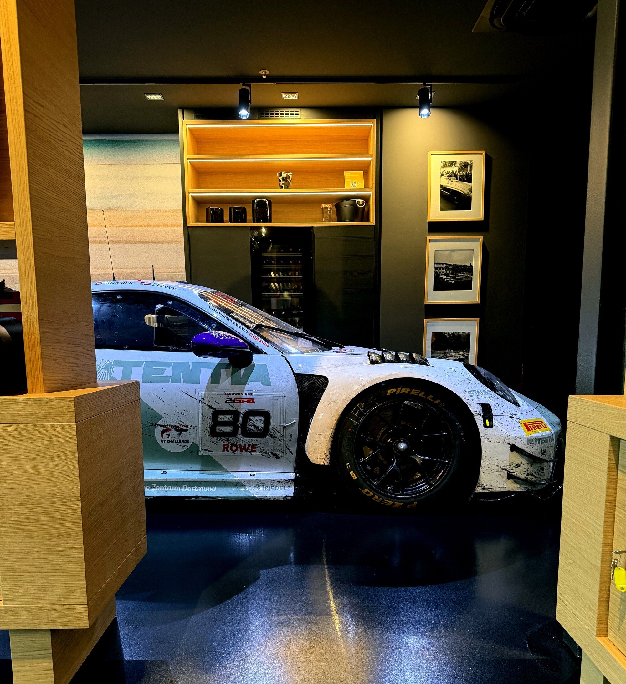 Porsche GT3 race car number 80 displayed in a warmly lit private showroom