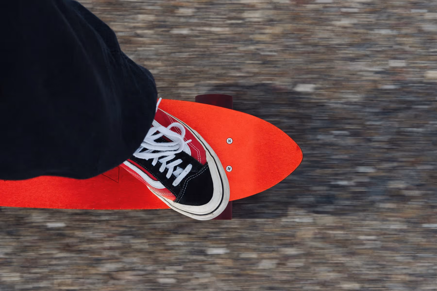 A rider’s red shoe on an aluminium skateboard