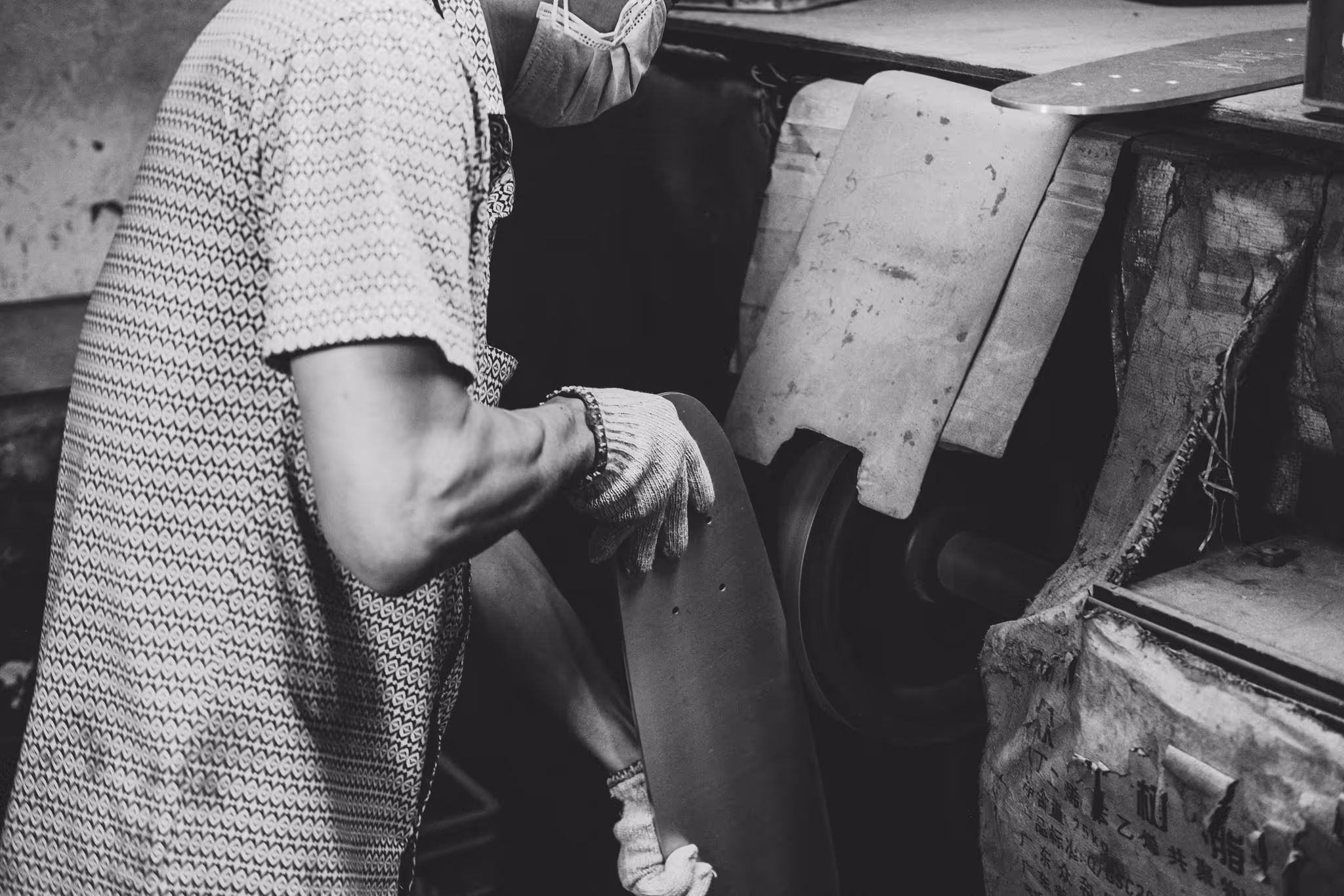Gloved hands finishing an aluminium skateboard deck at a polishing wheel